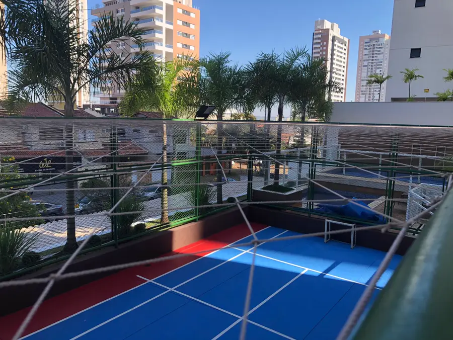 Quadra poliesportiva cercada com rede de proteção